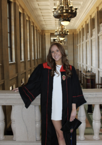 A woman smiles while wearing a black graduation gown.